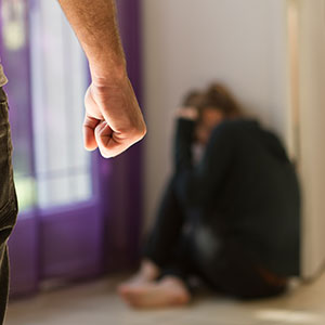 Man raising fist at woman cowering, symbolizing domestic violence legal help.