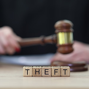 Wooden blocks spelling Theft with a gavel; legal defense for theft crimes in CO and CA.